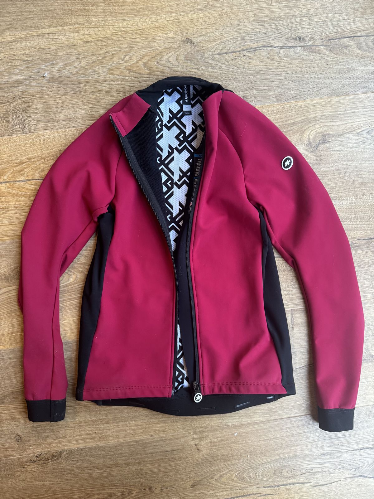 Flat lay of pink jacket with black accents and the zip half done showing internal white and black swirls