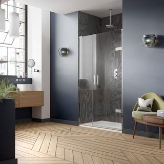 Bathroom with blue walls and wooden floorboards laid in different directions, large glass window with black panels and black patterned splashback in shower