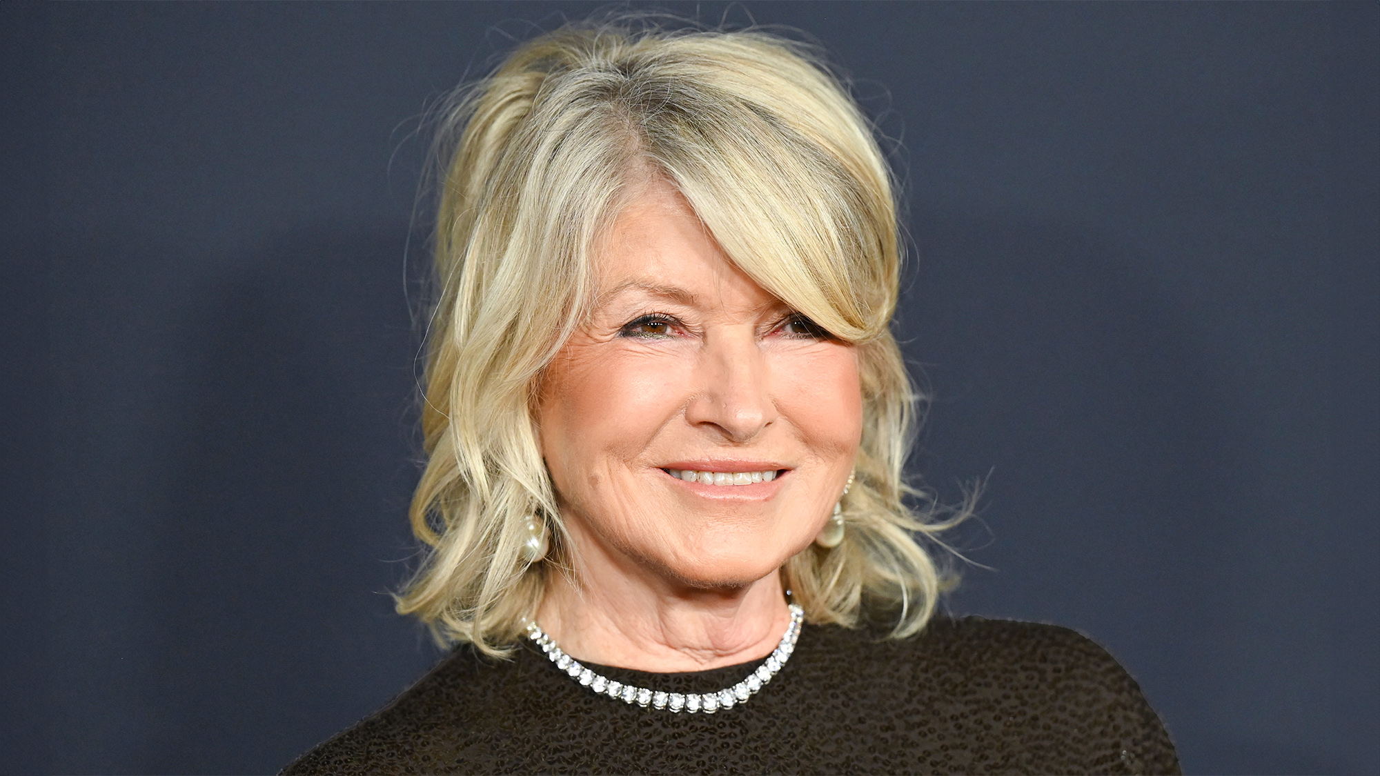 Martha Stewart at the Pre-Grammy Gala wearing black against dark background