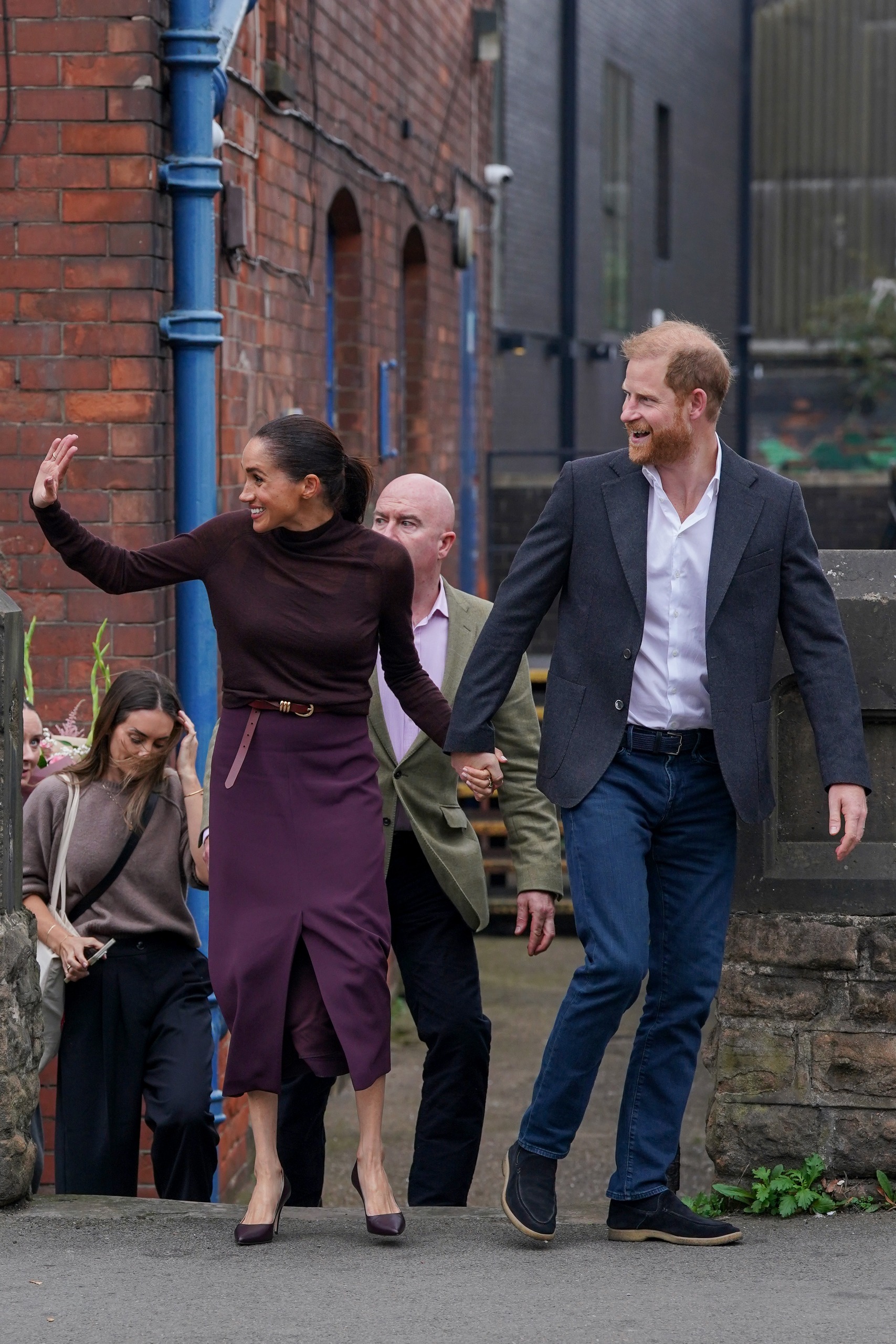 Meghan Markle and Prince Harry holding hands, waving and smiling
