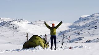 winter camping: a hiker celebrates after setting up camp