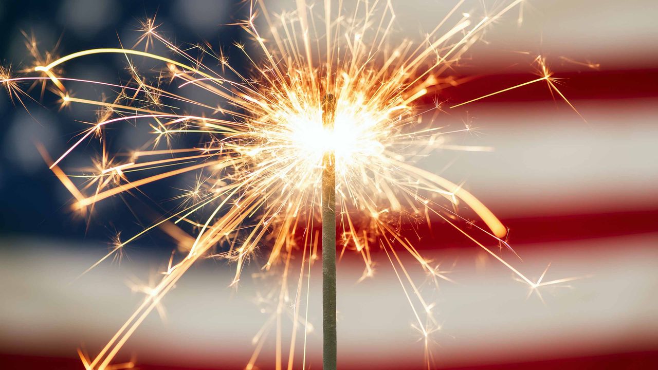 lit sparkler in front of american flag