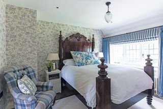 wooden bed in bedroom with arts and crafts style wallpaper