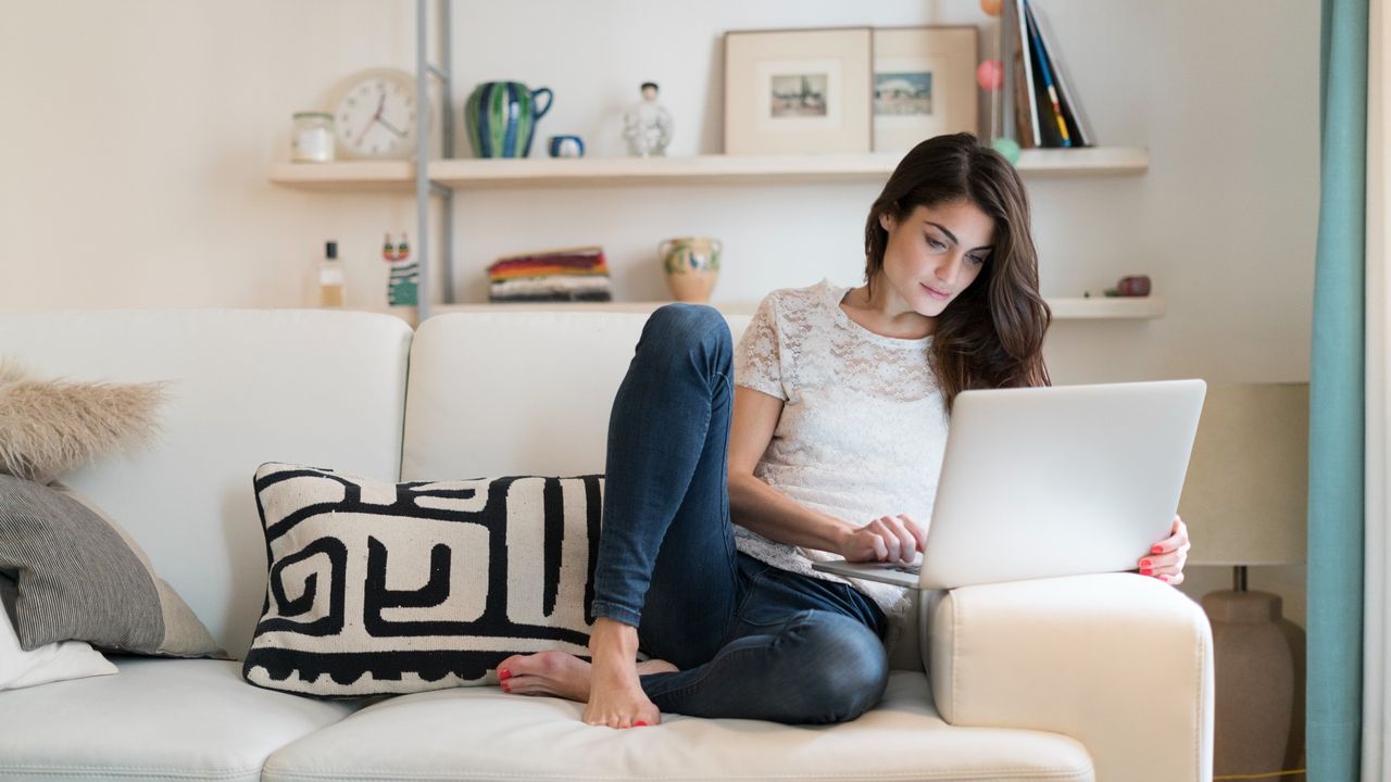 Woman on laptop on couch shopping for virtual gift 