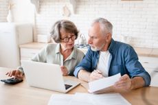 Older couple making calculations at home kitchen