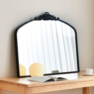black wide arched mirror sitting on a desktop