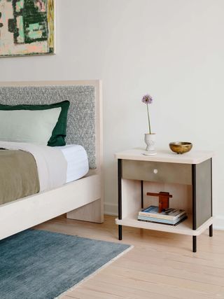 wooden bedside cabinet with drawer next to wooden bed