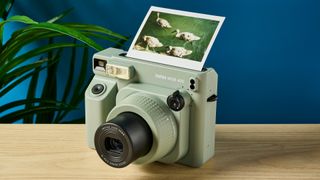 A sage green Fujifilm Instax Wide 400 instant camera