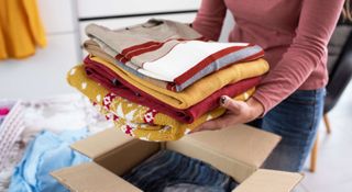 Woman placing seasonal clothes in a storage box