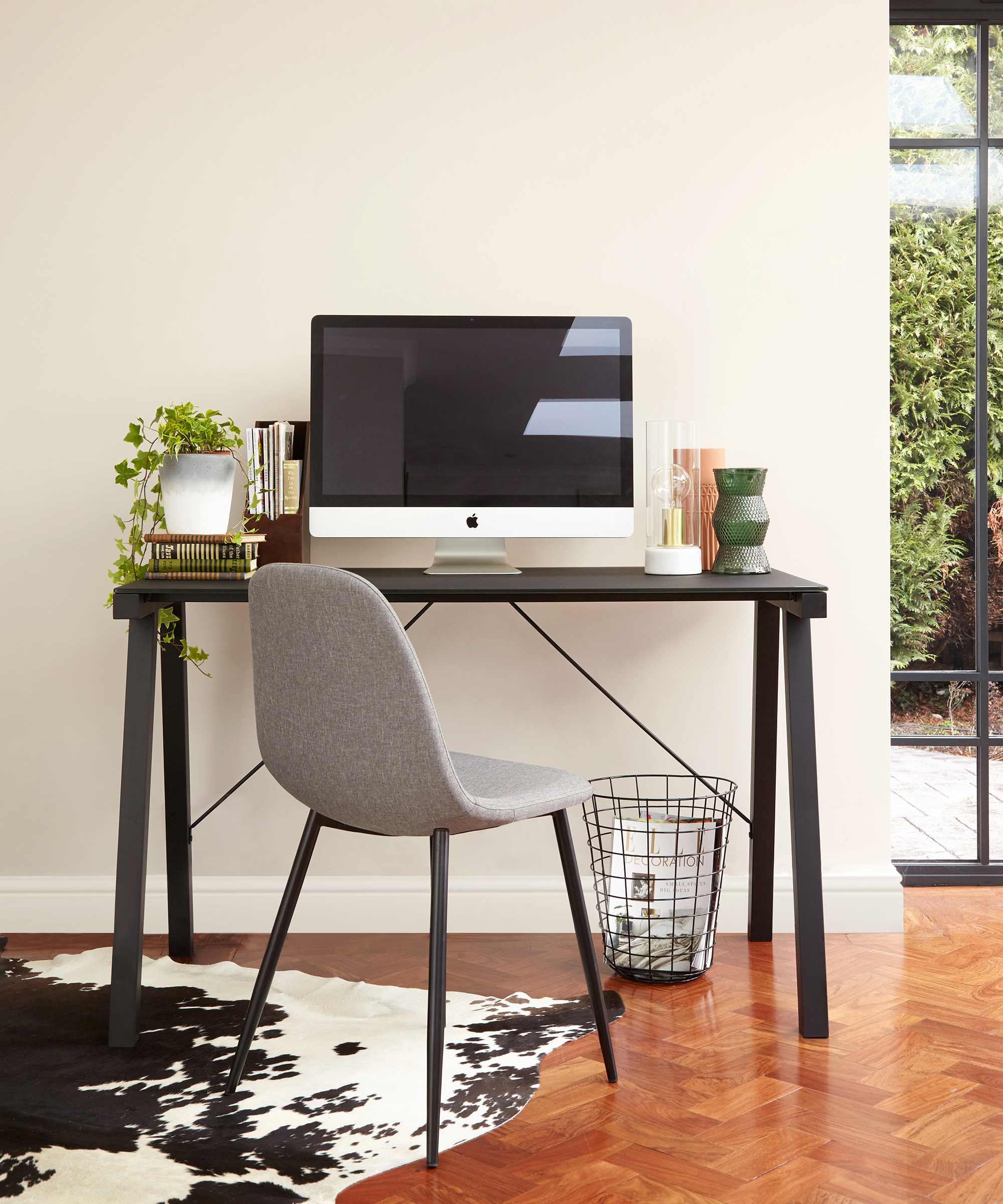 Black glass desk with waste bin, cow print rug and Apple Mac monitor by Danetti