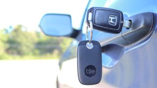 A Tile Pro Bluetooth key finder on a set of keys in a car door
