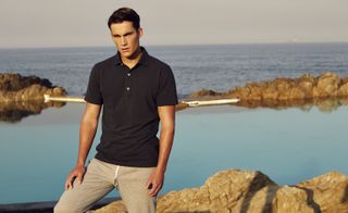 The DAVIS Tailored Poloshirt. A man standing with the sea behind him wearing casual clothing.
