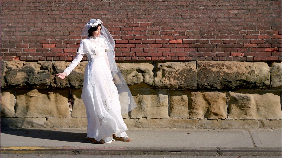 Bride trying to thumb a ride in her wedding dress.