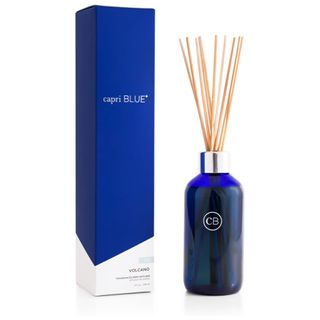 A capri blue volcano diffuser with blue bottle, wooden reeds, and blue box 