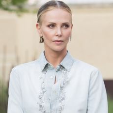Charlize Theron styled surprising ankle boots from Dior with a denim button-down and black mini skirt