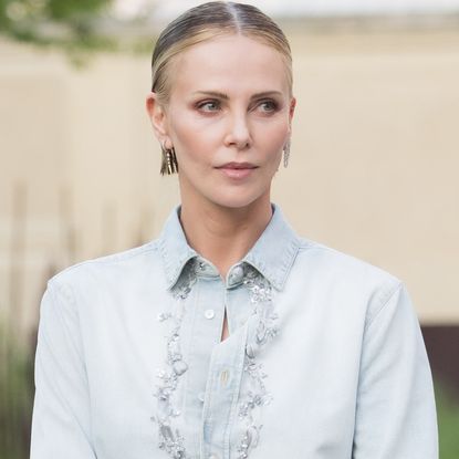 Charlize Theron styled surprising ankle boots from Dior with a denim button-down and black mini skirt