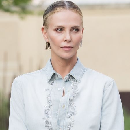 Charlize Theron styled surprising ankle boots from Dior with a denim button-down and black mini skirt