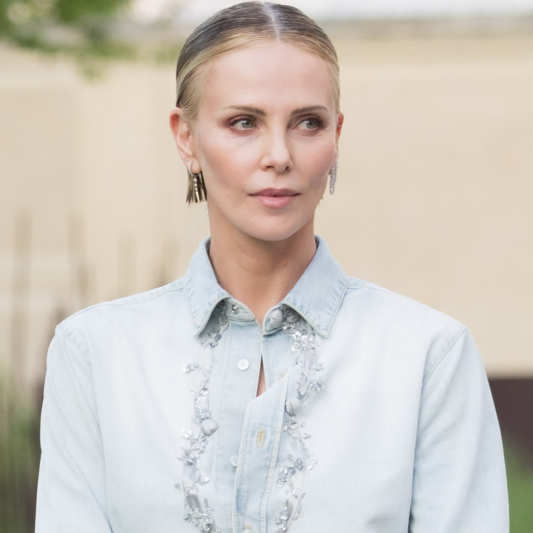 Charlize Theron styled surprising ankle boots from Dior with a denim button-down and black mini skirt