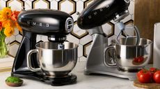 Two black stand mixers with stainless steel bowls on a marble kitchen counter. 