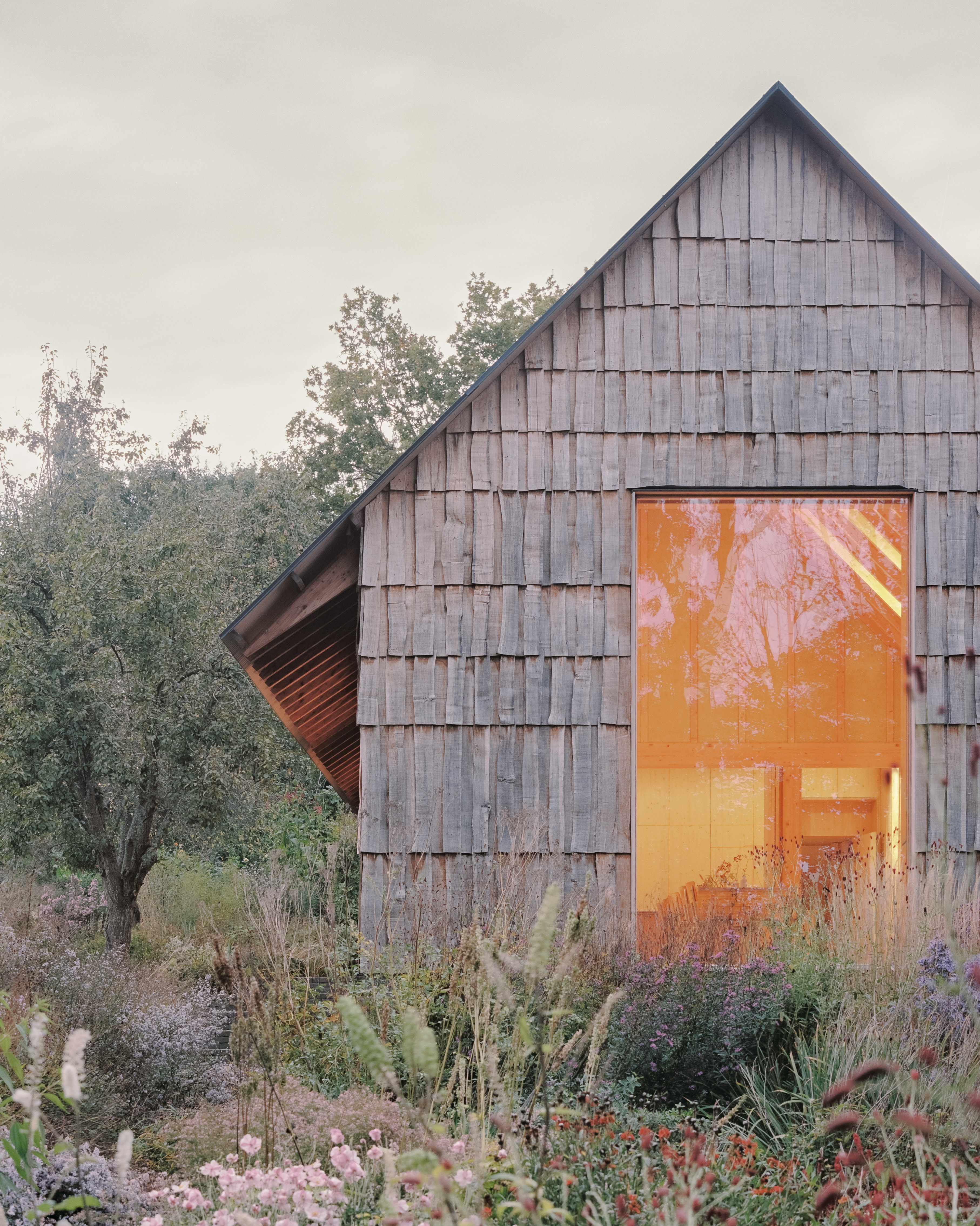 The Apple House, timber building with shingles and pitched roof set among wildflower fields