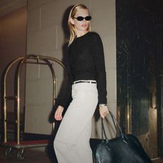 model wearing reformation 90s collection black jumper and white jeans