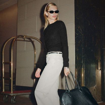 model wearing reformation 90s collection black jumper and white jeans