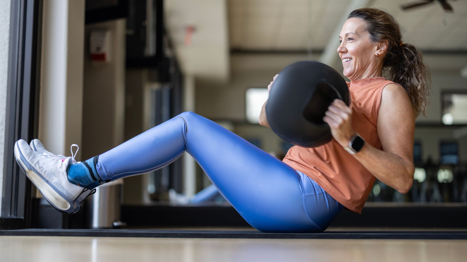 Woman doing Russian twist exercise in the gym with medicine ball sitting on yoga mat