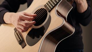 Close of Guitar Player team testing an acoustic guitar