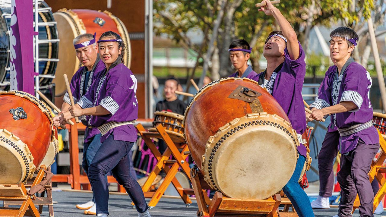 Japanese people banging Japanese drums