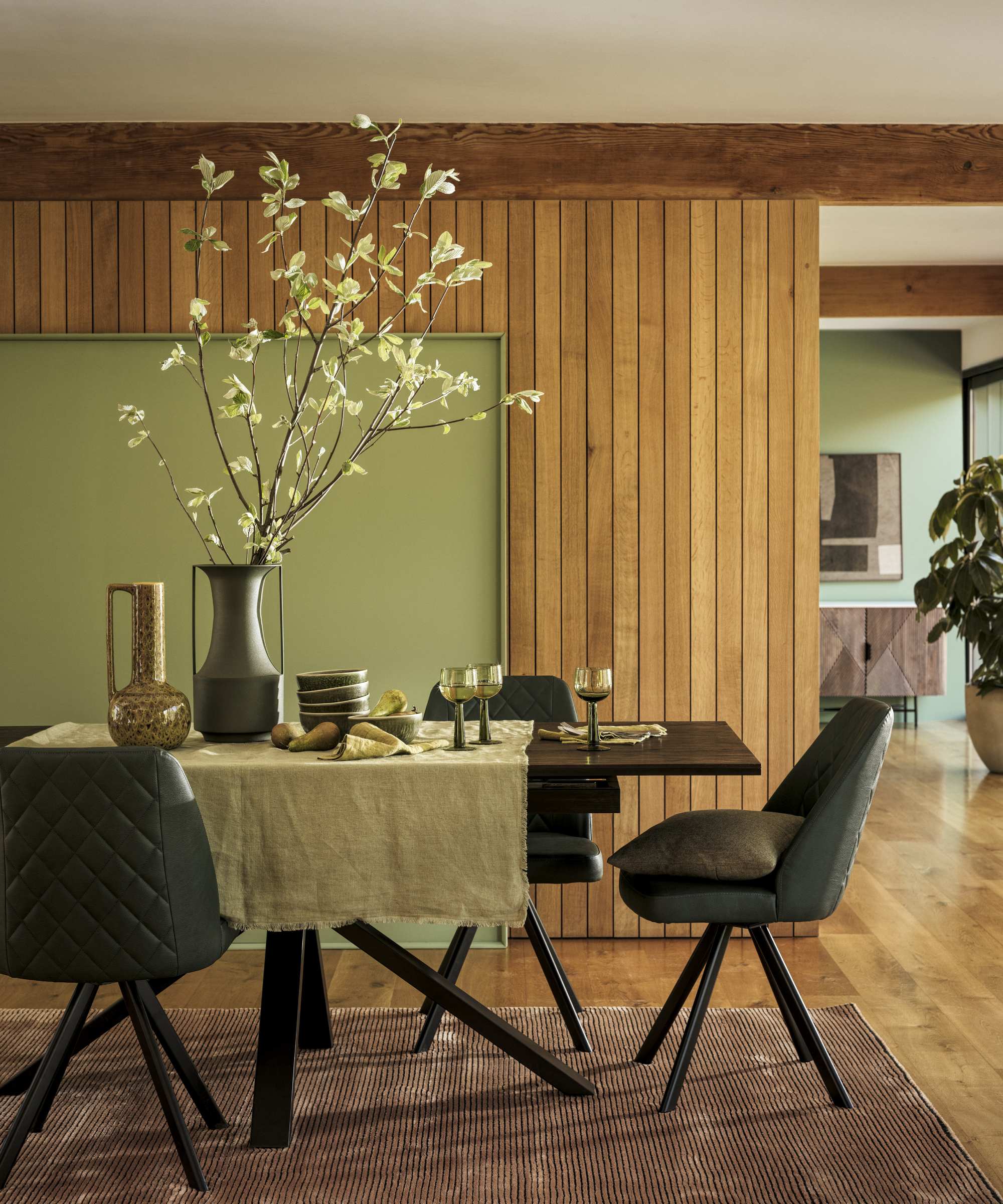 dining room with wooden vertical timber clad walls, green feature wall, table and chairs