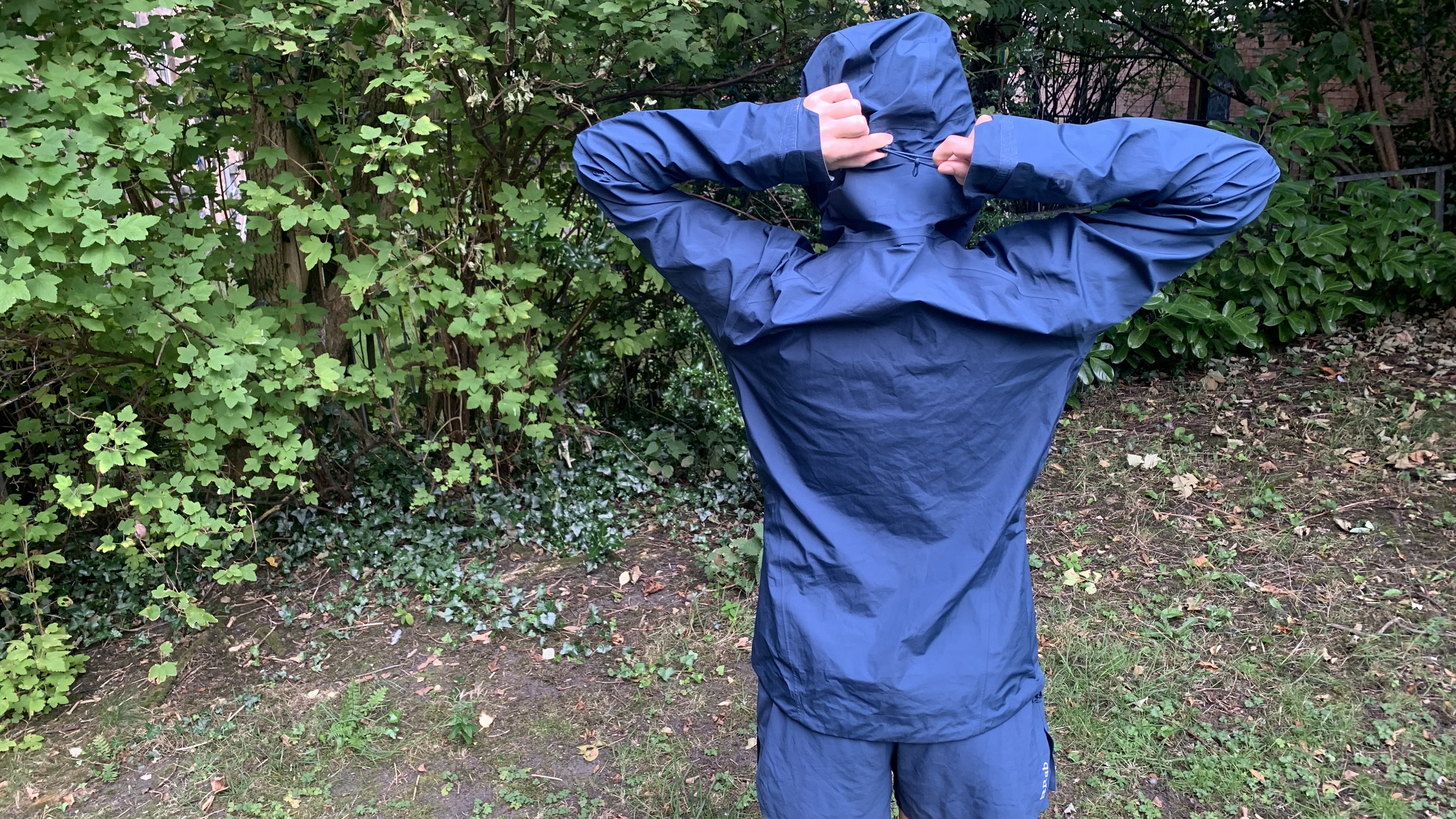 Hiker tightening the hood on the Rab Alpine Firewall Jacket