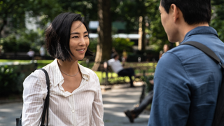 greta lee greets her childhood friend in a park in the movie past lives