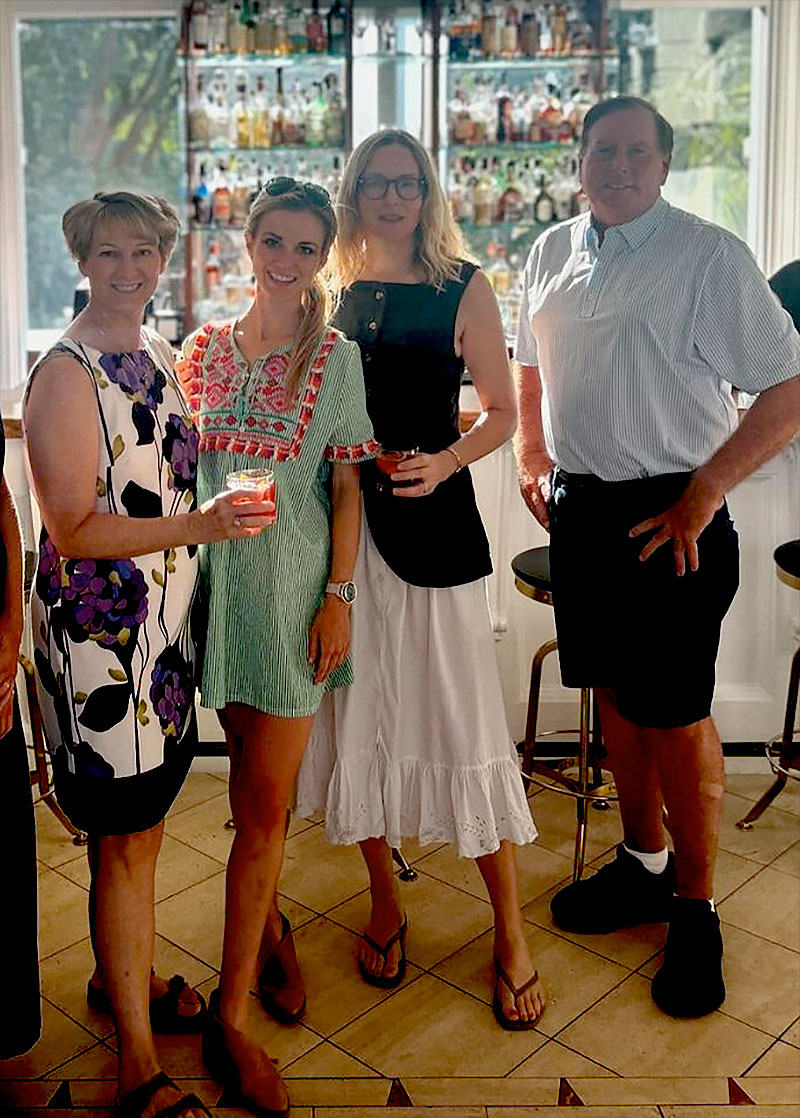 three women and a man stand in a well-lit kitchen