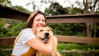 Woman hugging a dog outside smiling