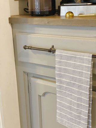 Light grey kitchen cabinet with silver handle and kitchen cloth