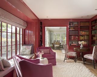 A pink living room with red-pink walls and armchairs