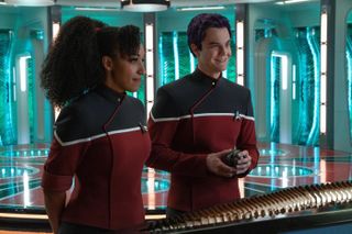 Two Star Trek officers in uniforms at the transporter pads