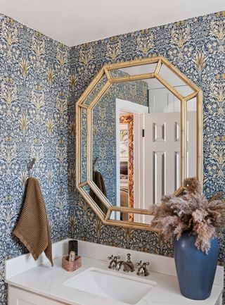 an ornate mirror in a wallpapered bathroom