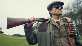 Lord Tony Baddingham (David Tennant) poses with a shotgun over his shoulder in &quot;Rivals&quot;