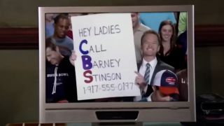 Neil Patrick Harris as Barney Stinson at the Super Bowl holding up a sign on TV on How I Met Your Mother