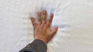 Reviewer's hand resting on PurpleFlex mattress