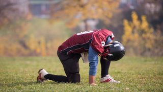 An American football player takes a break on the field.