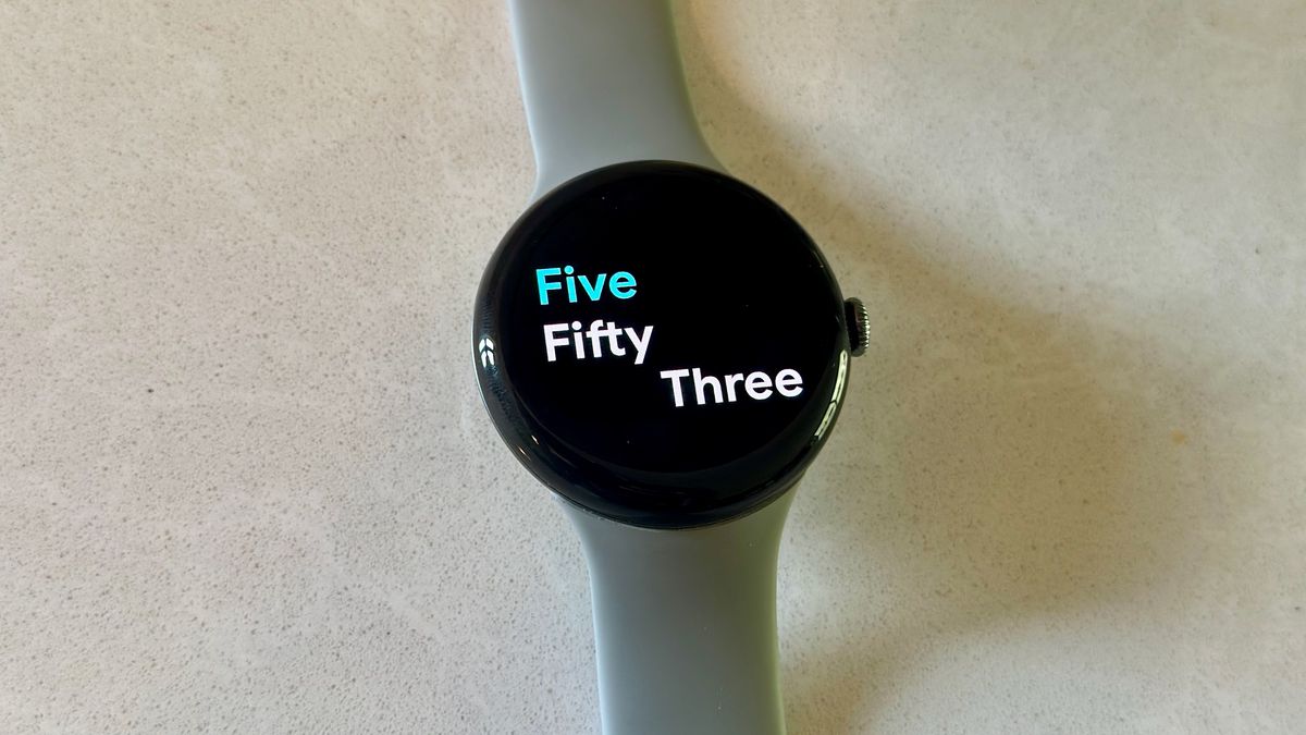 The Google Pixel Watch 3 on a white counter, showing the Prime watch face.