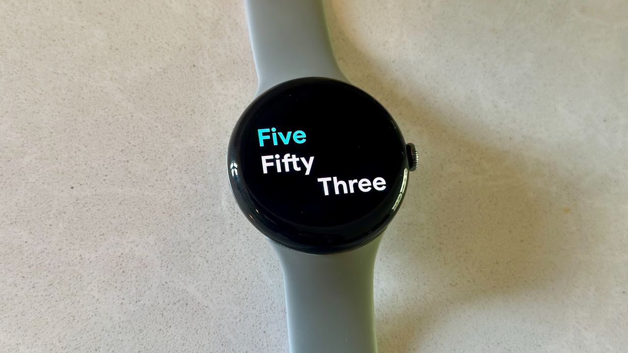 The Google Pixel Watch 3 on a white counter, showing the Prime watch face.