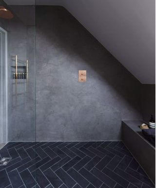 Black herringbone floor tiles with a grey shower wall