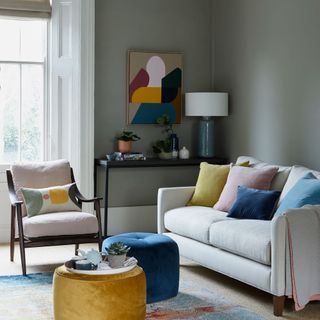 grey living room with sofa, colourful footrests and artwork