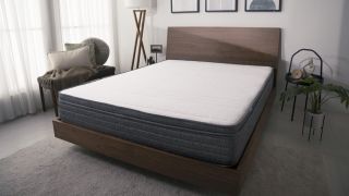 The Origin Hybrid Mattress on a wood frame bed in a modern bedroom