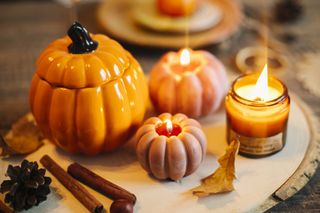 A wooden board with pumpkin shaped candles on it.