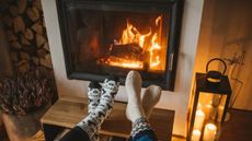 Two pairs of cozy socked feet in front of a roaring fireplace with clean glass