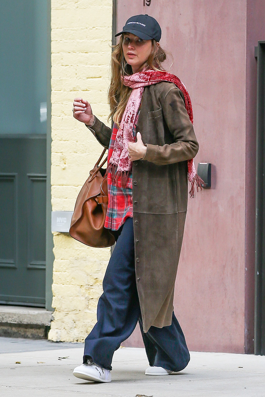Jennifer Lawrence wearing a brown suede coat, scarf, plaid shirt, navy pants, and white sneakers
